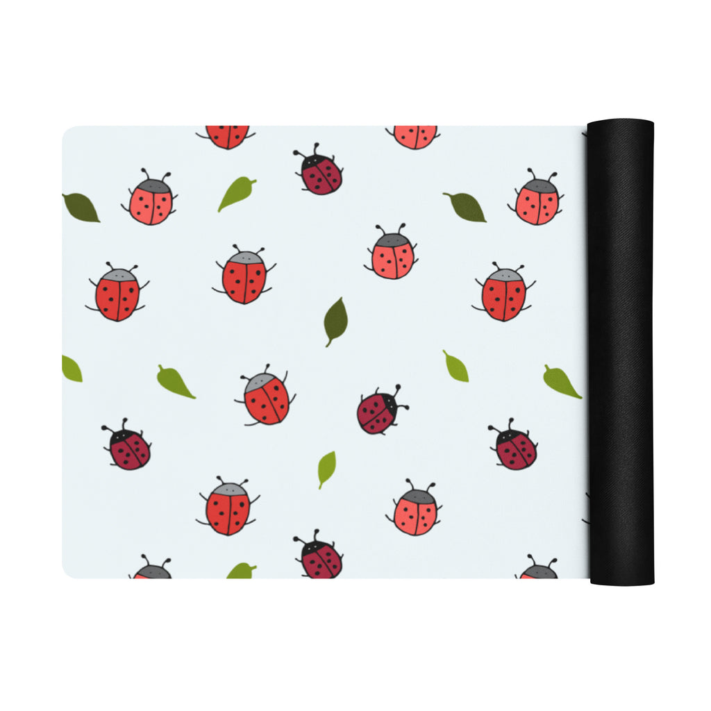 Ladybird print yoga mat on a neutral background. Red ladybirds or ladybugs with green leaves. 
